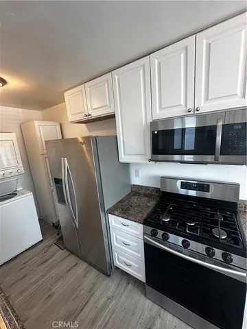 a kitchen with granite countertop a refrigerator stove and white cabinets