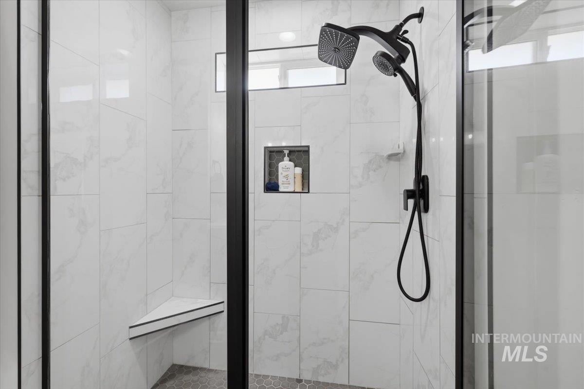 918 Sierra Street Vale, OR 97918 - Photo 28 of 42 Walk-in shower with a black-framed glass enclosure, white tiled walls, a corner bench, recessed niche, and matte black shower fixtures