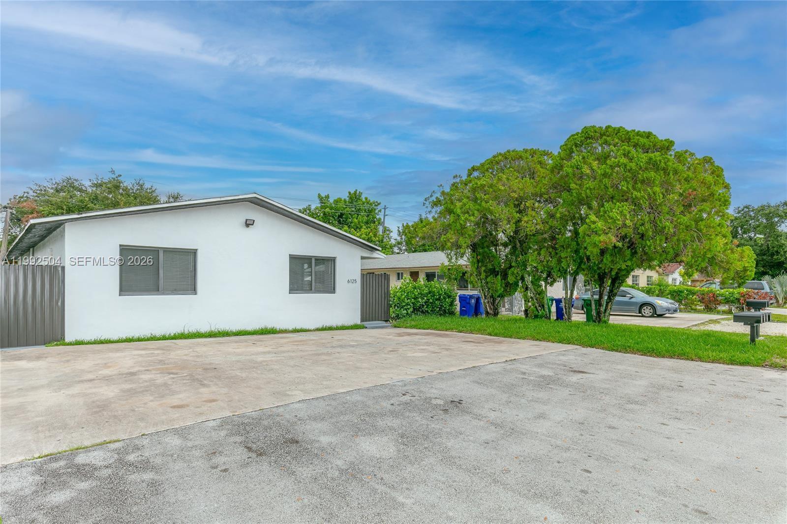 a view of a house with a yard and large trees