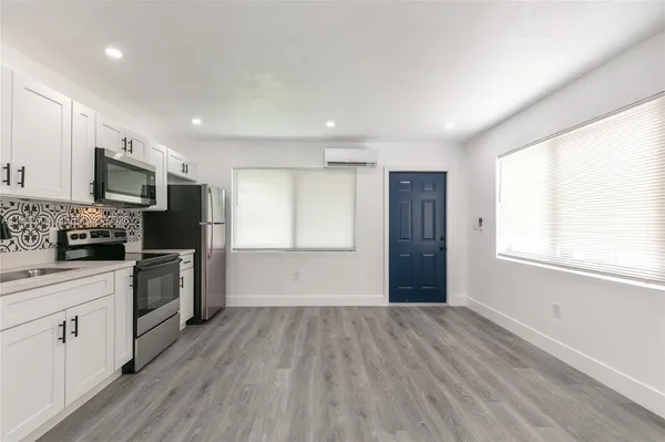 a kitchen with a refrigerator wooden floor and white cabinets