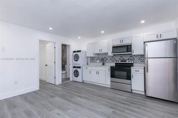 a kitchen with a refrigerator a stove top oven and white kitchen