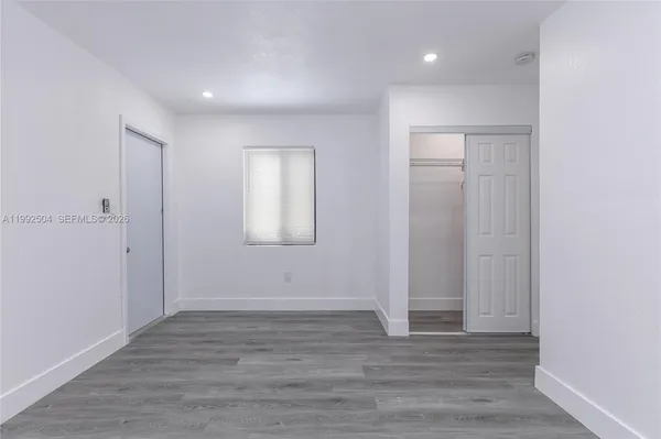 a view of an empty room with wooden floor and closet
