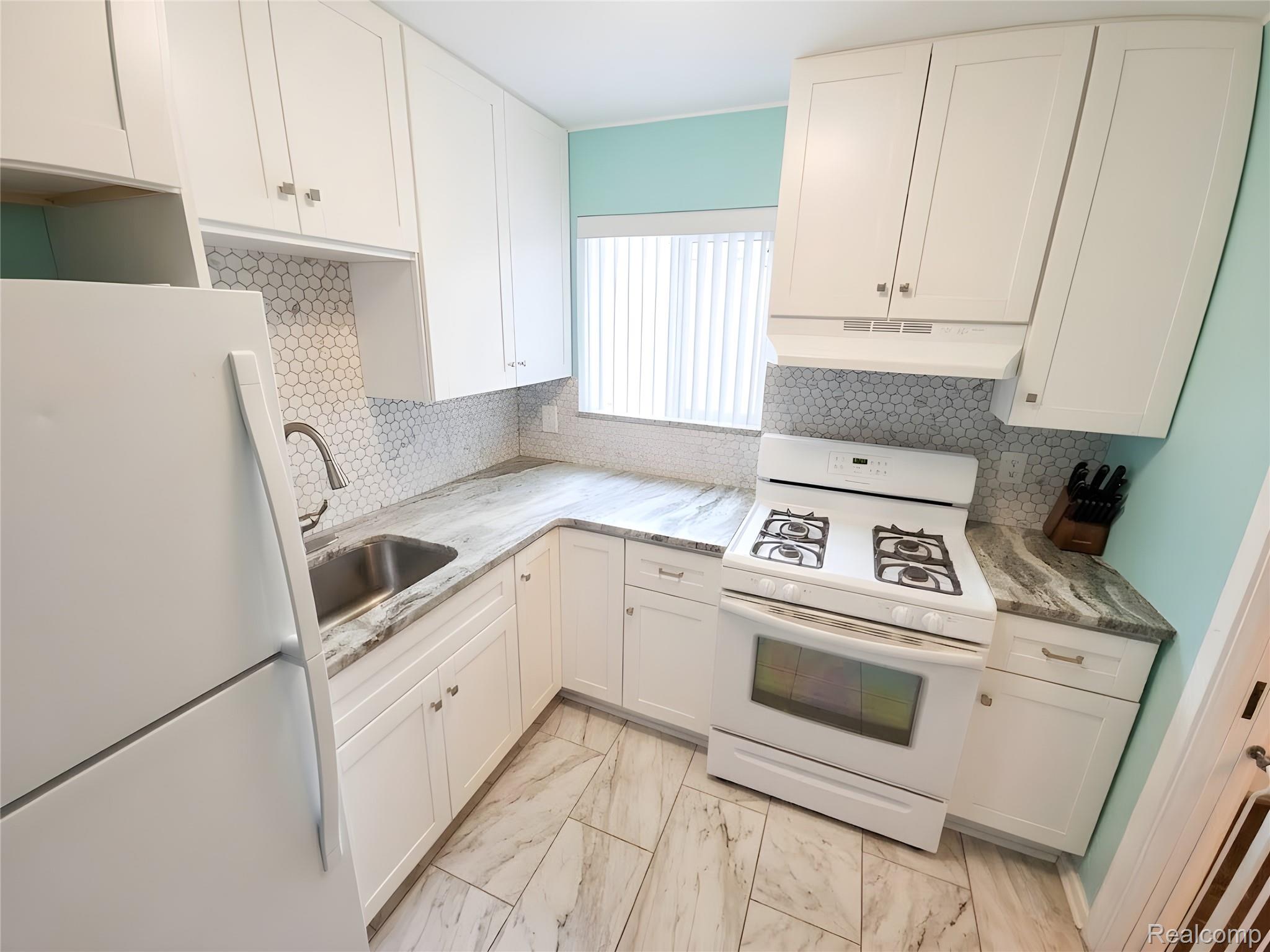 9921 Middlebelt Road, Unit 32 Livonia, MI 48150 - Photo 4 of 11 Kitchen featuring white cabinetry, hexagonal tile backsplash, light-toned countertops, and wood-finish tile flooring