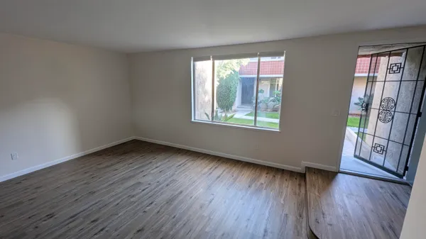 a view of an empty room with wooden floor and a window