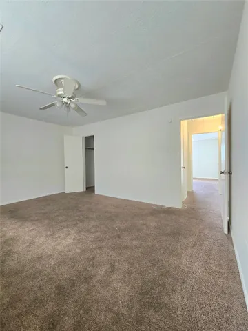 an empty room with a ceiling fan and window