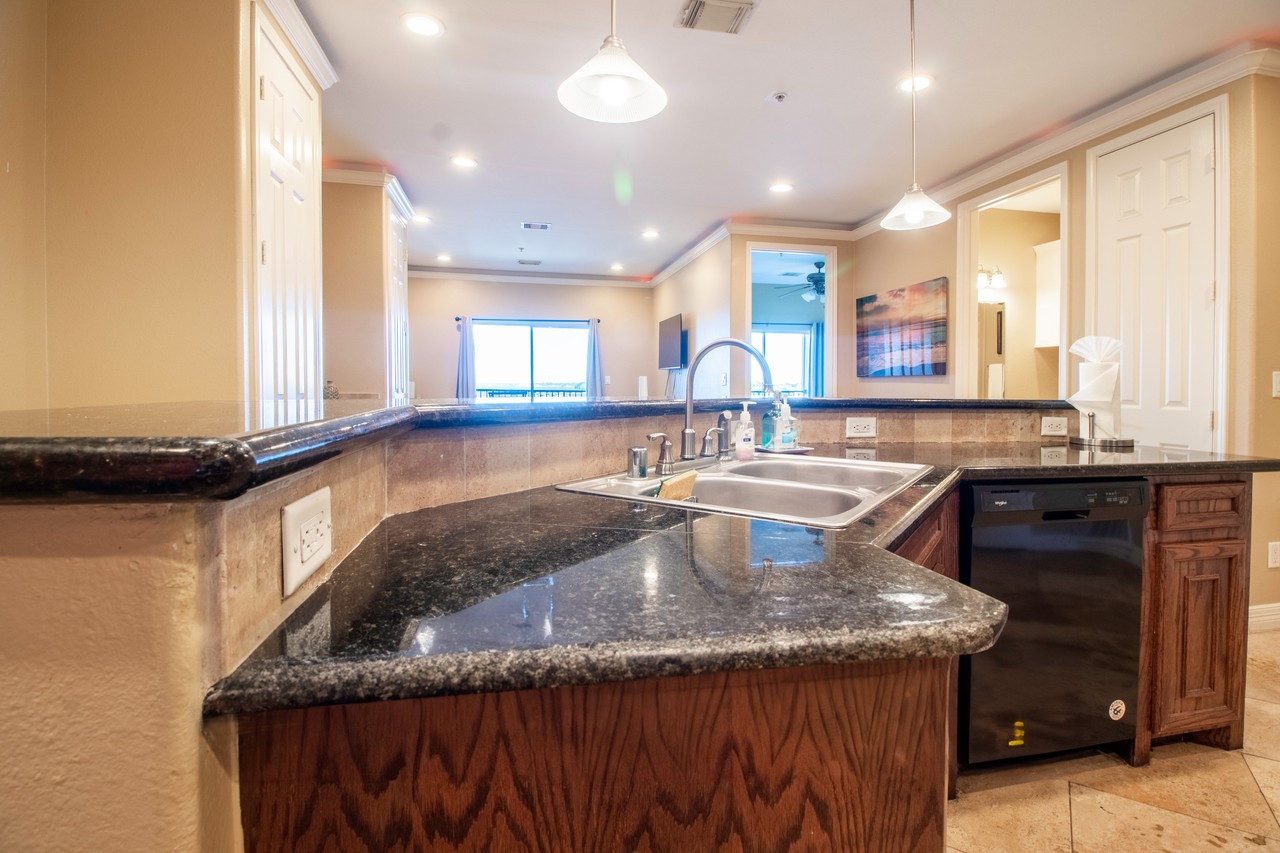 7039 Kingston Cove Lane, Unit 307 Willis, TX 77318 - Photo 3 of 11 a kitchen with granite countertop a sink a counter and window