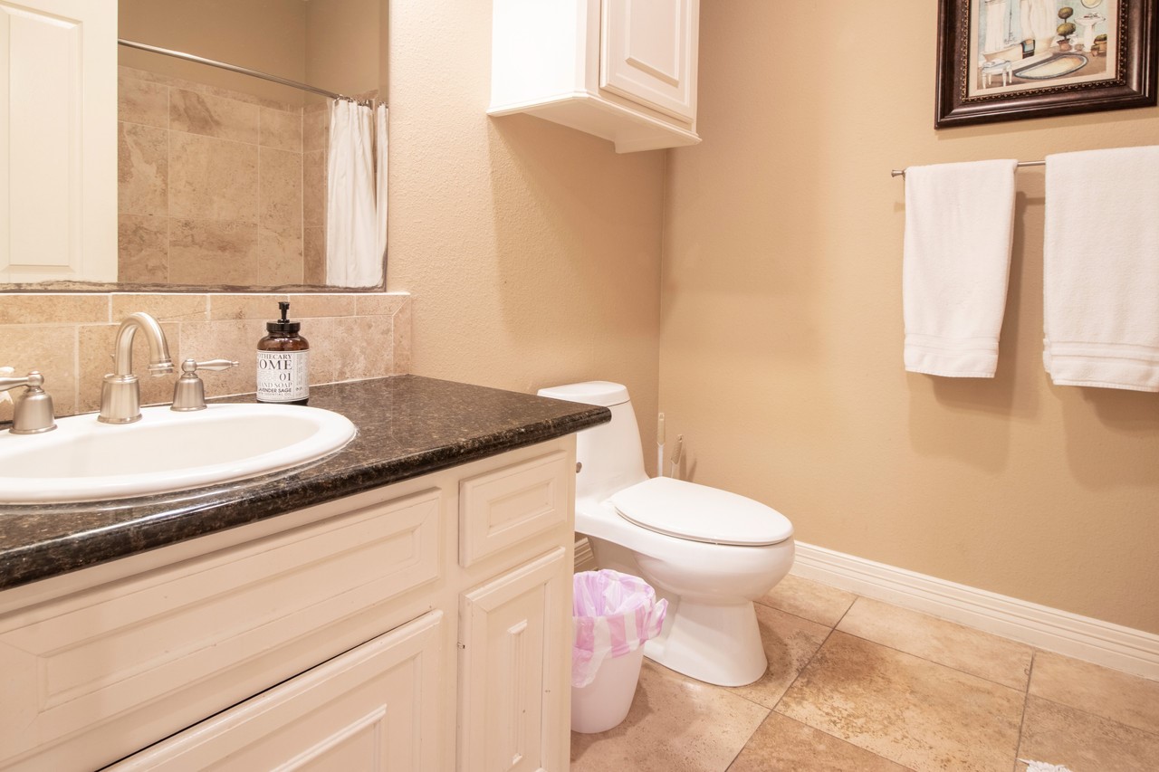 7039 Kingston Cove Lane, Unit 307 Willis, TX 77318 - Photo 10 of 11 a bathroom with a granite countertop toilet sink and mirror