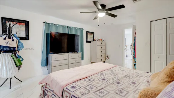 a bedroom with a bed a flat screen tv and a chandelier
