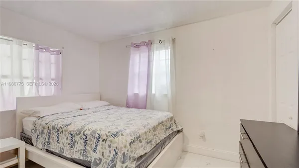 a bedroom with a bed and a window with chair