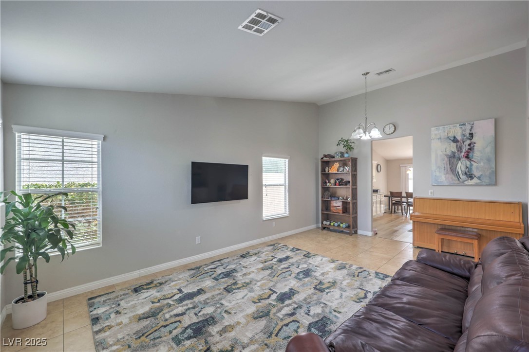 47 Trailside Court Henderson, NV 89012 - Photo 5 of 26 Living room with light tile patterned floors, a chandelier, and ornamental molding