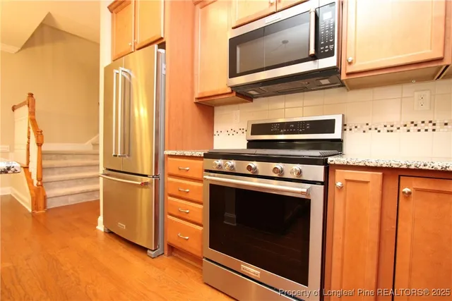 a kitchen with stainless steel appliances granite countertop a stove microwave and refrigerator