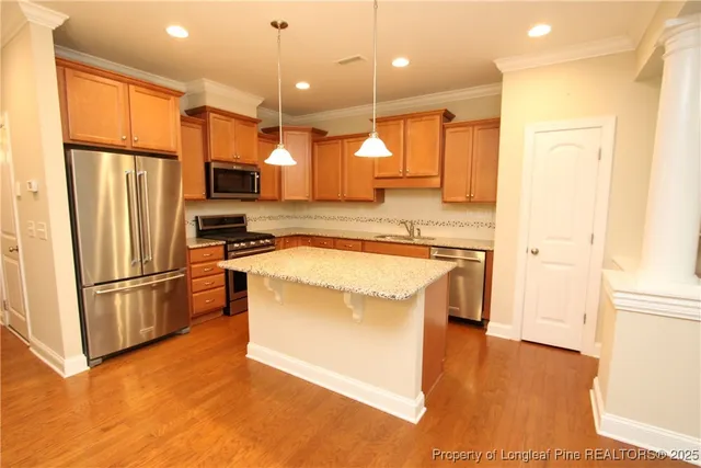 a kitchen with kitchen island a counter top space a refrigerator a sink and a stove