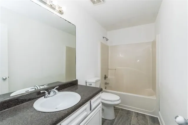 a bathroom with a granite countertop sink toilet a mirror and shower