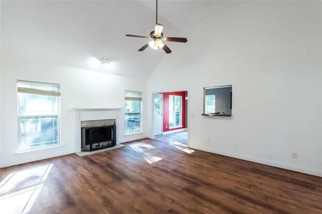 a view of an empty room with wooden floor fireplace and a window