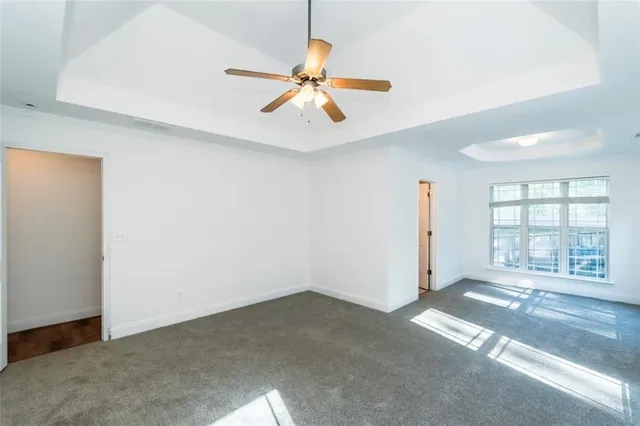 an empty room with windows and ceiling fan