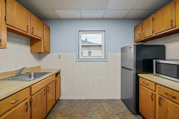 a kitchen with stainless steel appliances granite countertop a refrigerator a stove and a sink with wooden cabinets