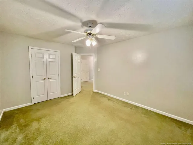 an empty room with closet and a ceiling fan