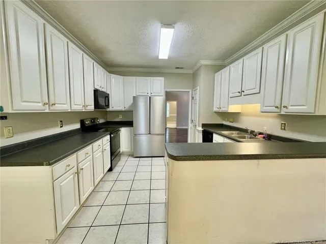 a kitchen with stainless steel appliances granite countertop a sink a stove a refrigerator a window and white cabinets