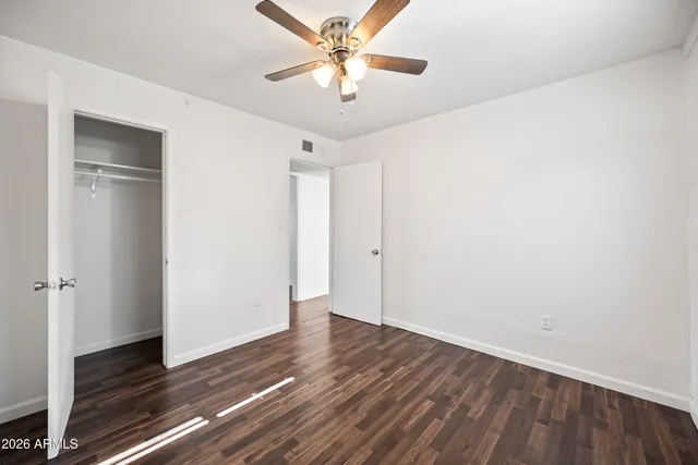 a view of an empty room with window and wooden floor