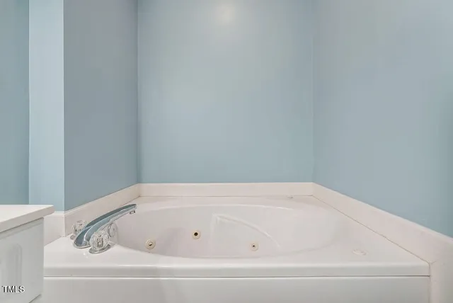 an empty room with a chandelier fan and windows