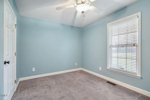 an empty room with windows and fan