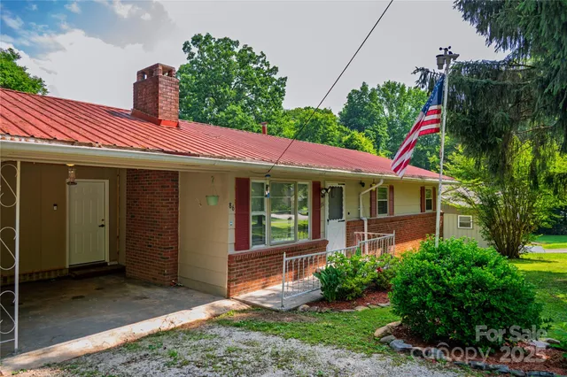 a view of a house with a yard potted plants and a bench