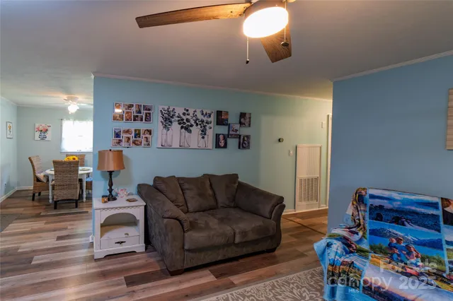 a living room with furniture and a dining table with wooden floor