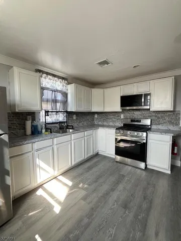 a kitchen with granite countertop a stove a sink and a microwave