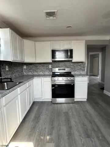 a kitchen with stainless steel appliances wooden floor sink and a microwave