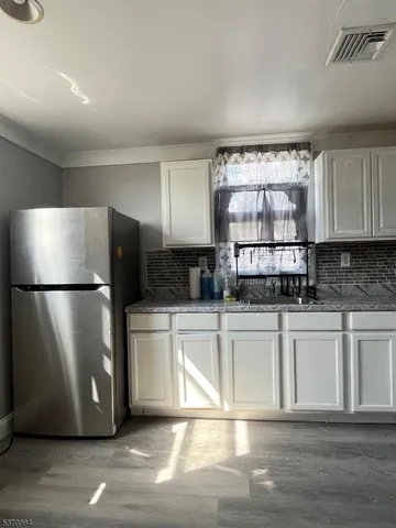 a kitchen with stainless steel appliances granite countertop a refrigerator sink and white cabinets