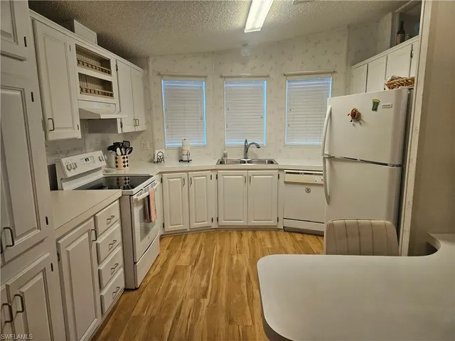 a kitchen with stainless steel appliances a refrigerator sink and white cabinets
