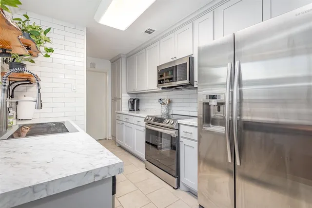 a kitchen with kitchen island a counter top space cabinets and stainless steel appliances