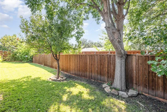 a view of a yard with wooden fence and a large tree