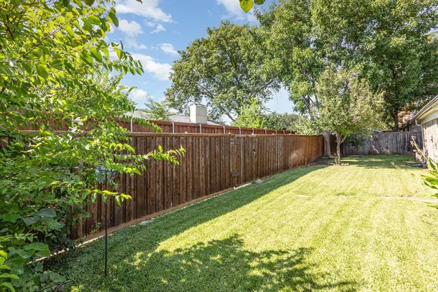 a view of a backyard with wooden fence and large trees