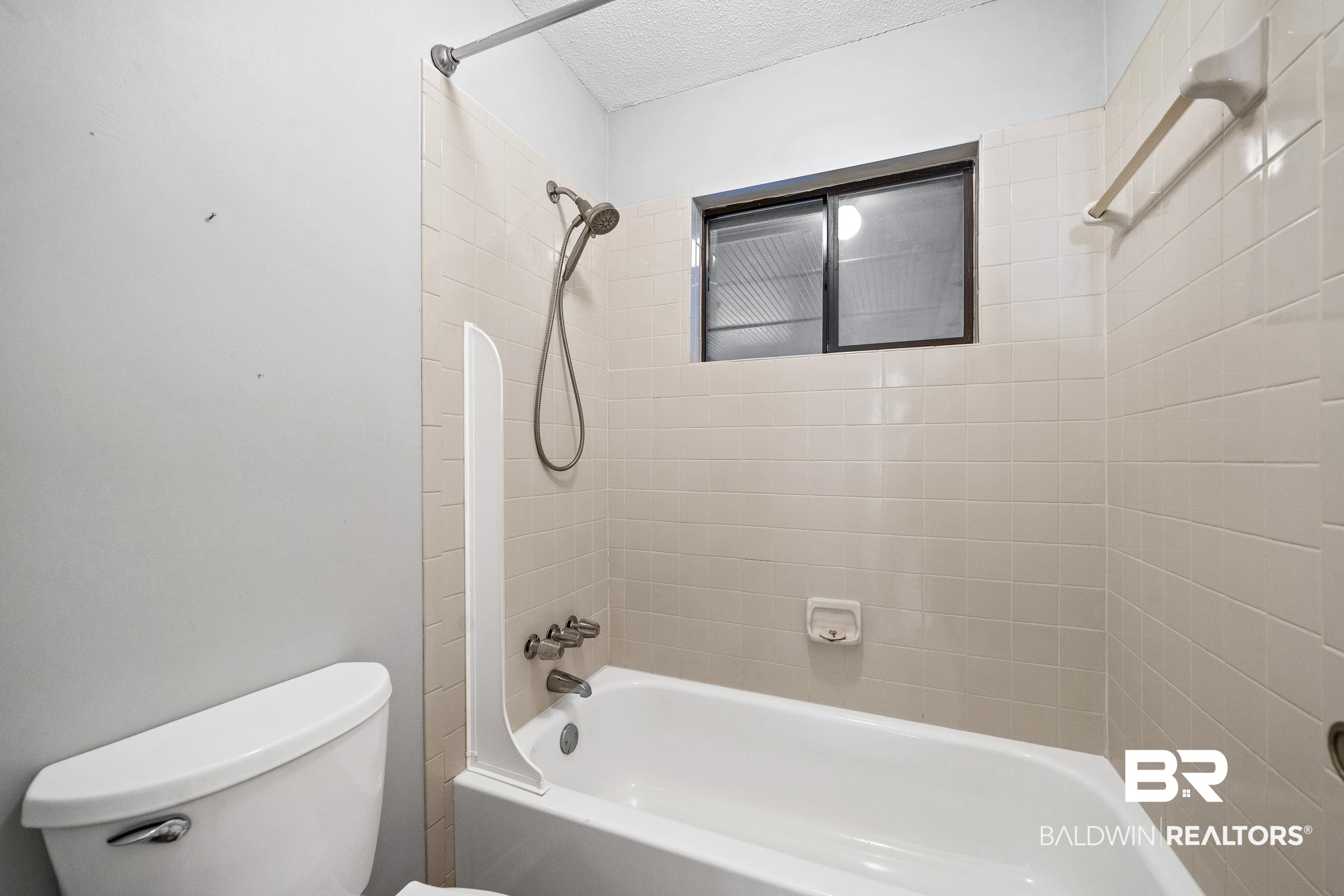 511 Ridgewood Drive Daphne, AL 36526 - Photo 25 of 59 Bathroom featuring toilet, tiled shower / bath, and a textured ceiling