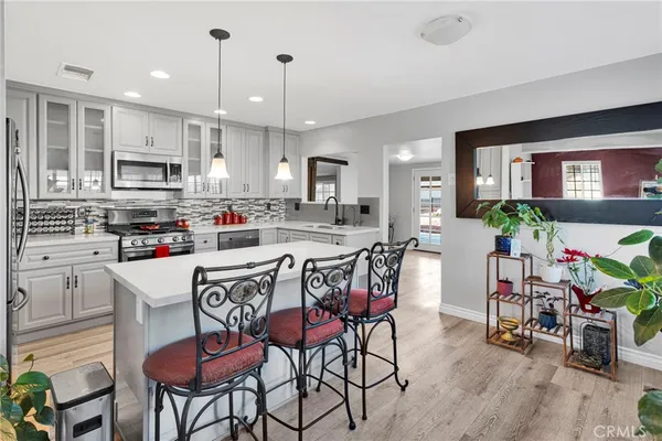 a kitchen with stainless steel appliances granite countertop a stove top oven a refrigerator a sink and chairs