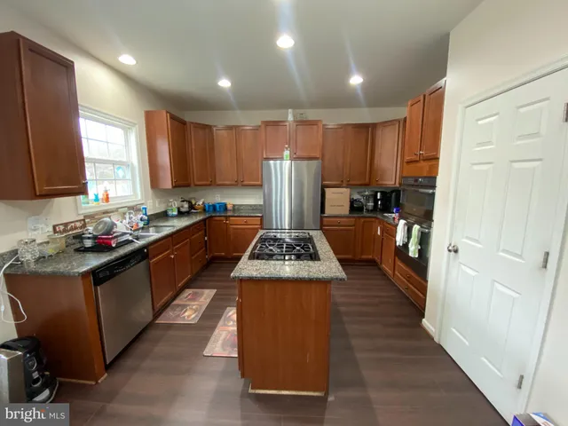 a kitchen with kitchen island granite countertop wooden cabinets a sink a stove and a refrigerator