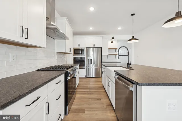 a kitchen with stainless steel appliances granite countertop a sink a stove and a refrigerator