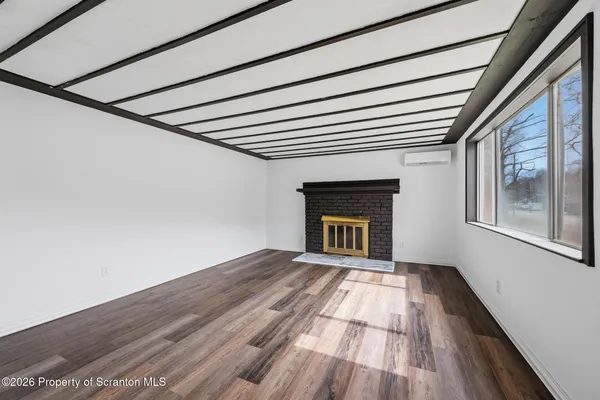 a view of empty room with wooden floor and fireplace