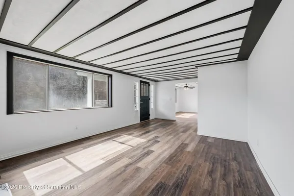 a view of an empty room with wooden floor and a window