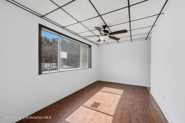 a view of a hallway with wooden floor and a bathroom