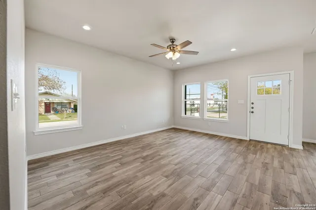 a view of an empty room with a window and wooden floor