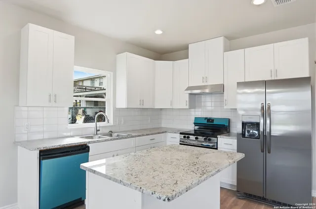 a view of a kitchen with a sink and refrigerator
