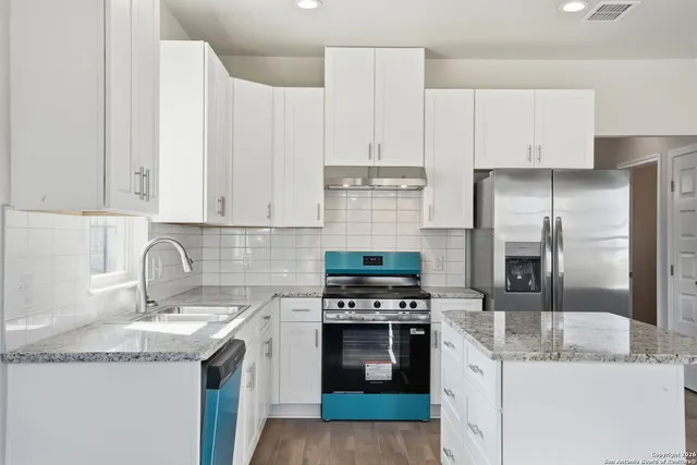 a view of an empty room with wooden floor and windows