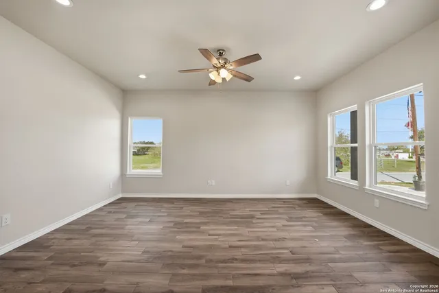 an empty room with wooden floor and ceiling fan