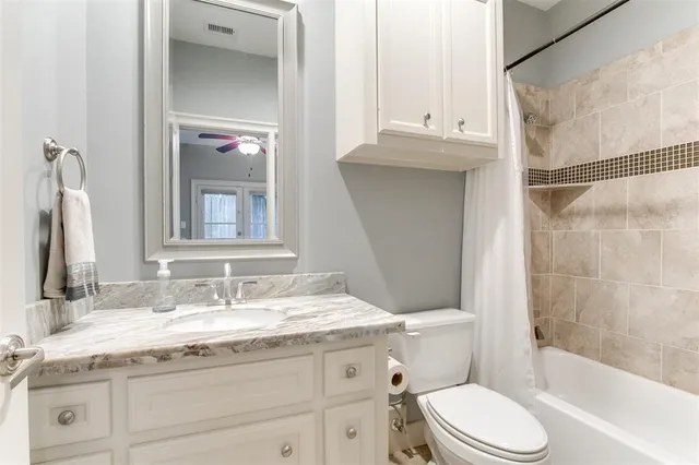 a bathroom with a granite countertop sink toilet mirror and bathtub
