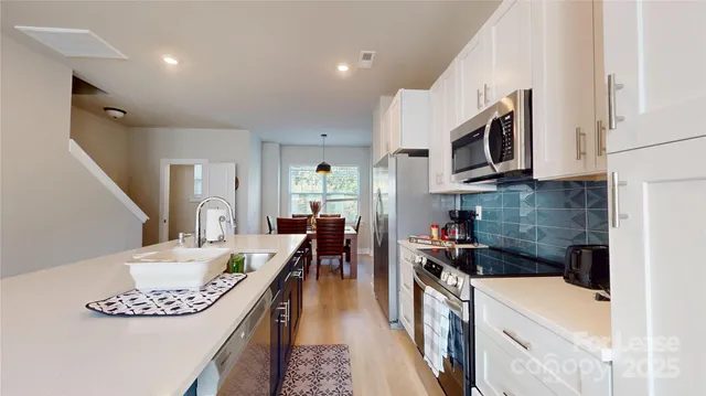 a kitchen with stainless steel appliances granite countertop a white cabinets a stove top oven a sink and dishwasher