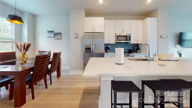 a kitchen with stainless steel appliances kitchen island granite countertop a table and chairs