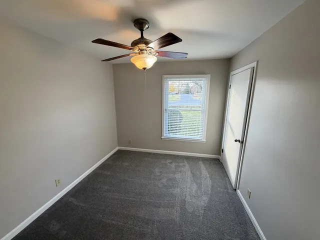 an empty room with a window and a fan