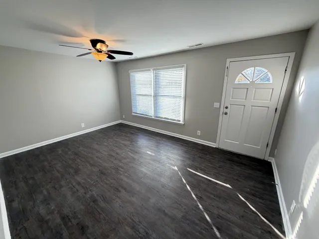 a view of empty room with wooden floor and window